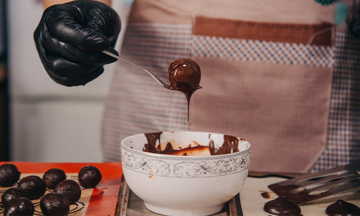 Pessoa retirando um bombom banhado com cobertura de chocolate